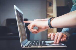two persons collaborating in front of a laptop