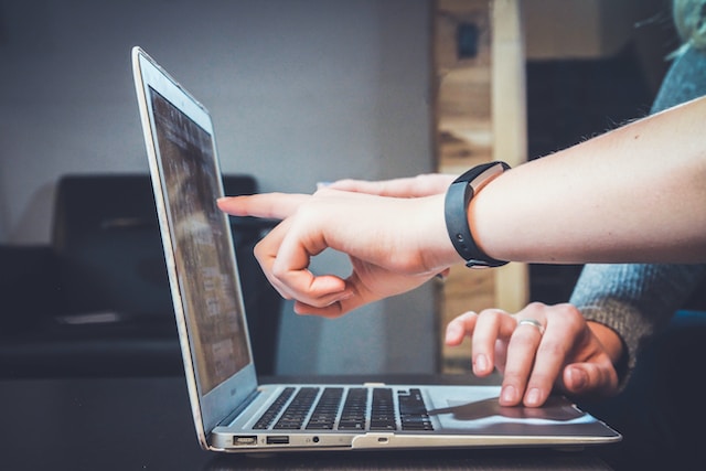 two persons collaborating in front of a laptop
