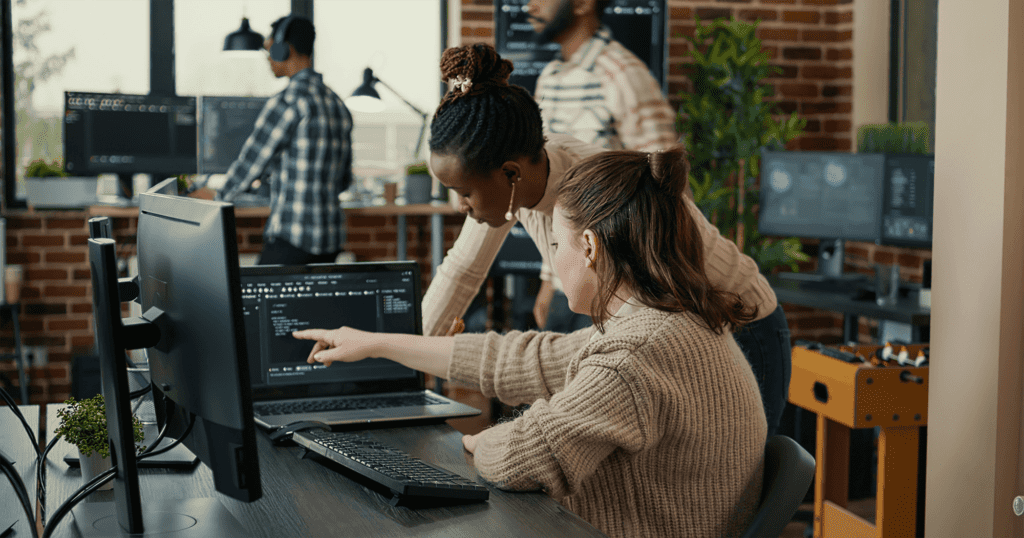 Two women working together on a monitor